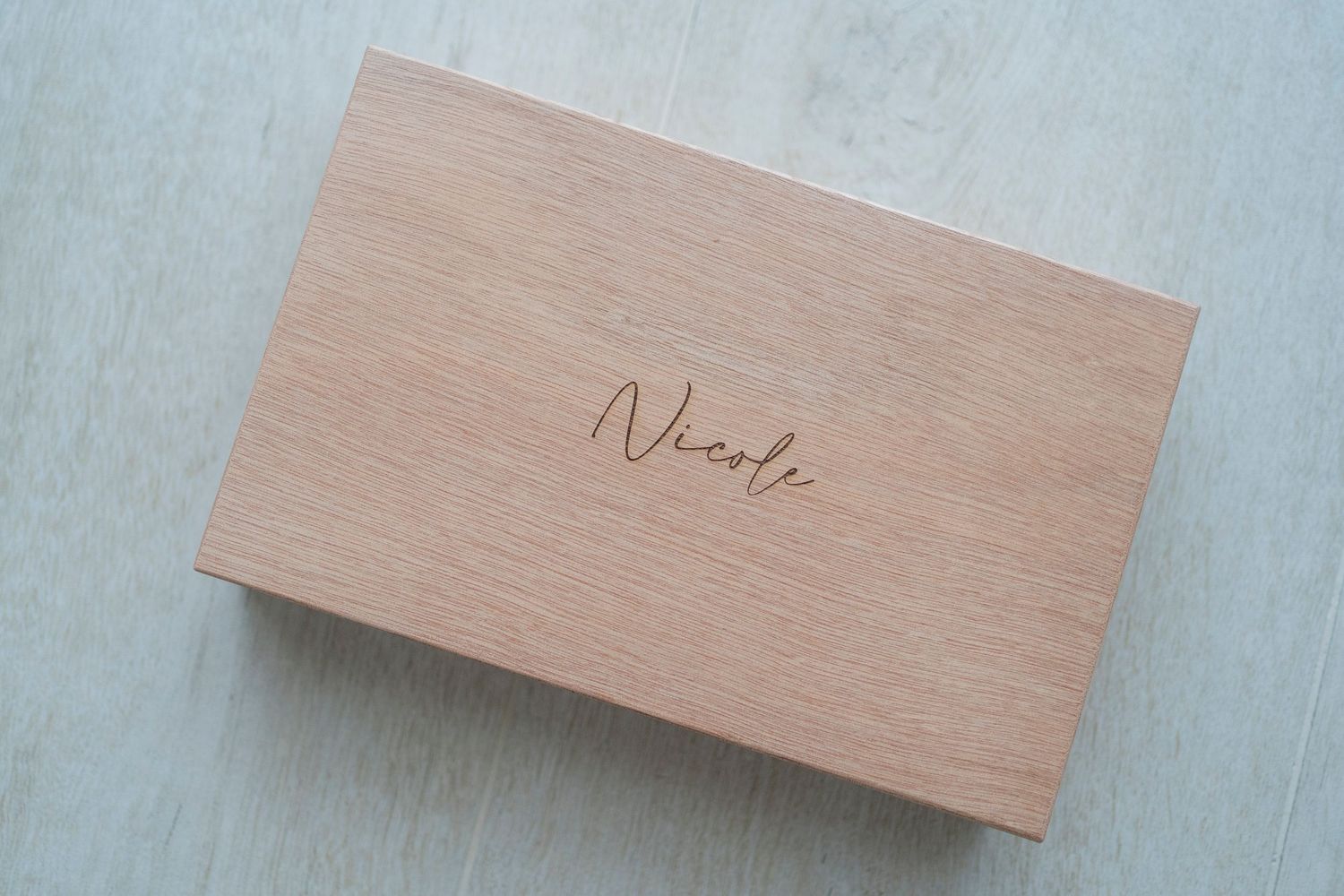 Personalized wooden keepsake box engraved with name Nicole on light surface.