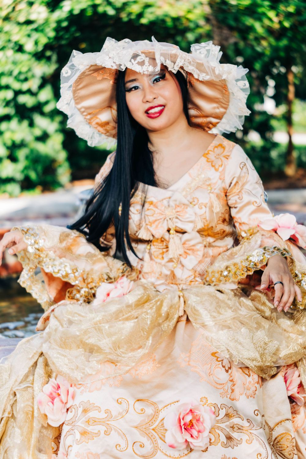 Elegant portrait in ornate golden Marie Antoinette style dress with lace bonnet.