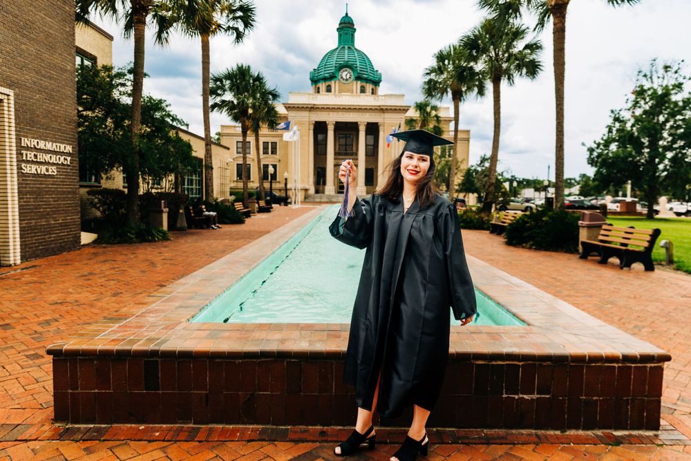 A graduation photo taken in front of a collegiate building with green domed architecture.