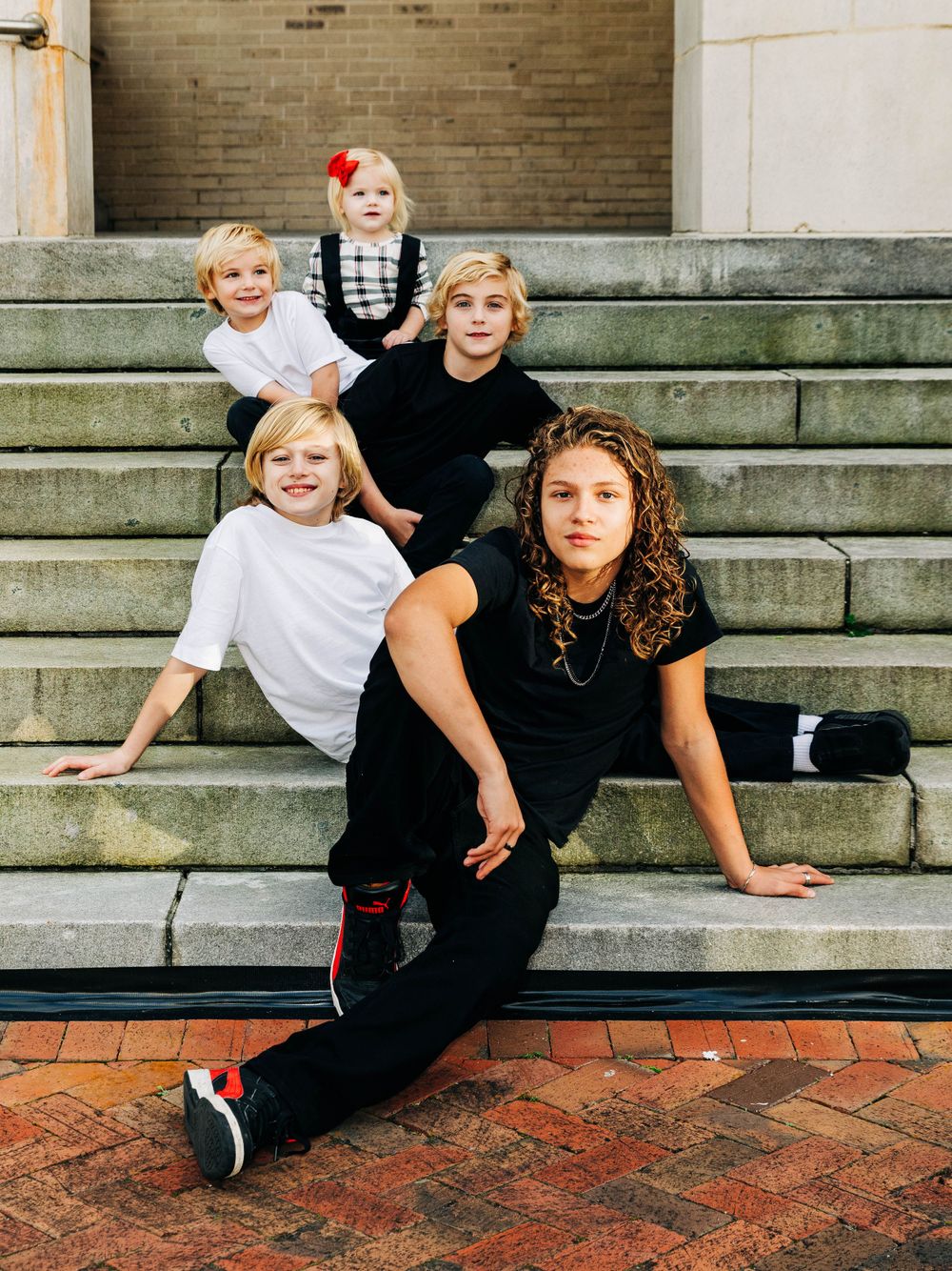 Group sitting casually on stone steps wearing black and white casual outfits.