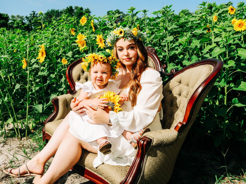 A vintage settee placed in a sunflower field creates a whimsical outdoor portrait setting.