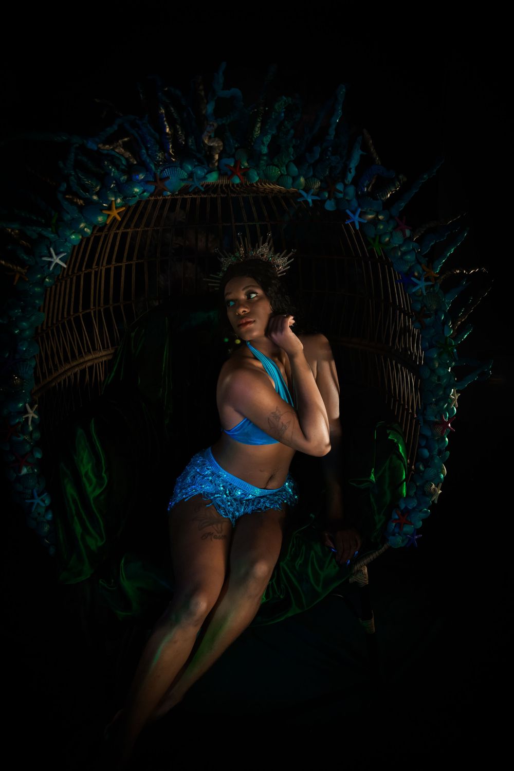 A performer in blue posing dramatically in front of an illuminated floral arch.