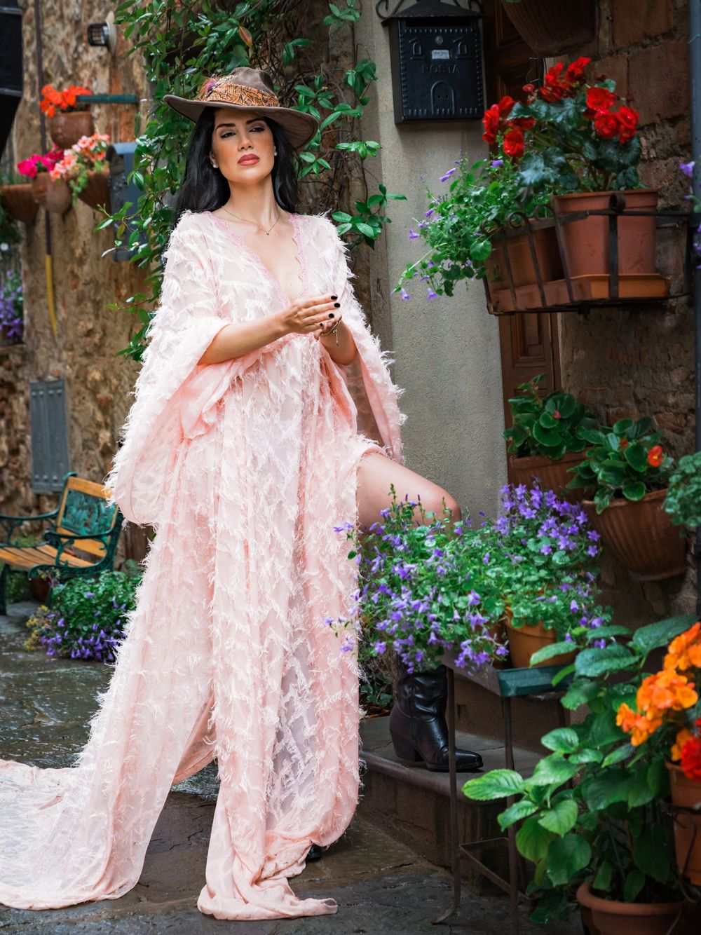 Ornate pink lace dress photographed in garden setting with colorful flowers.