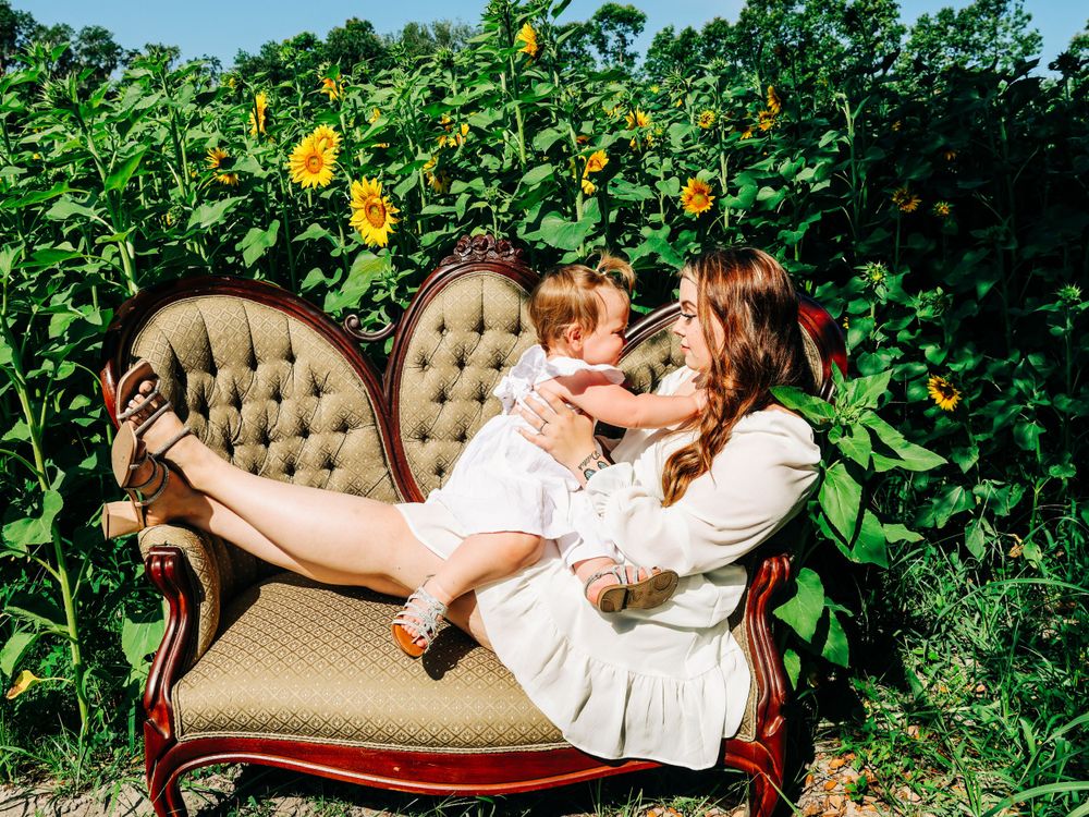 A heartwarming scene on an antique sofa surrounded by towering sunflowers.