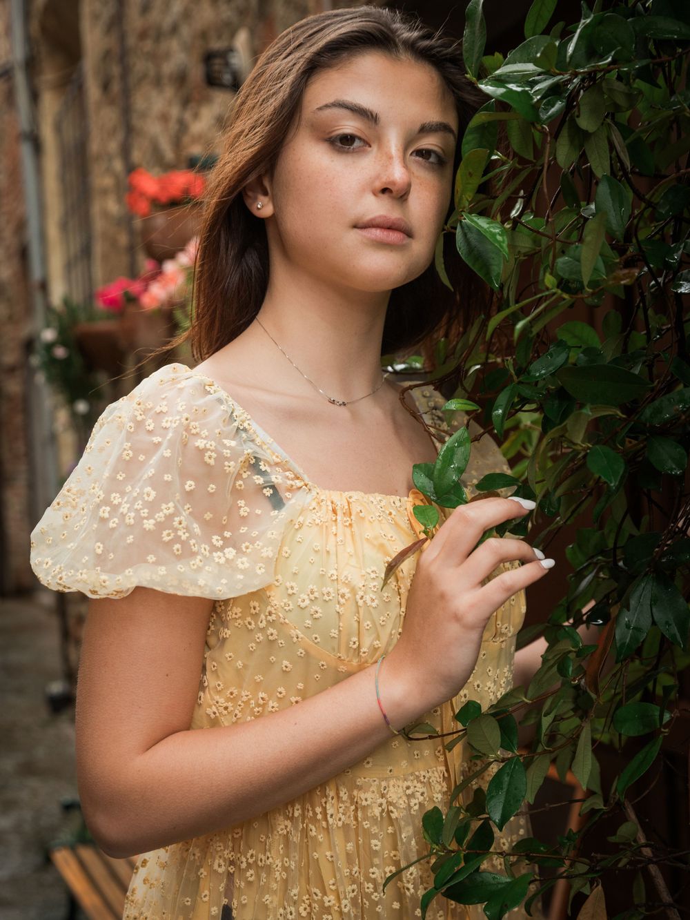 A vintage-inspired portrait featuring a yellow lace dress against stone architecture and greenery.