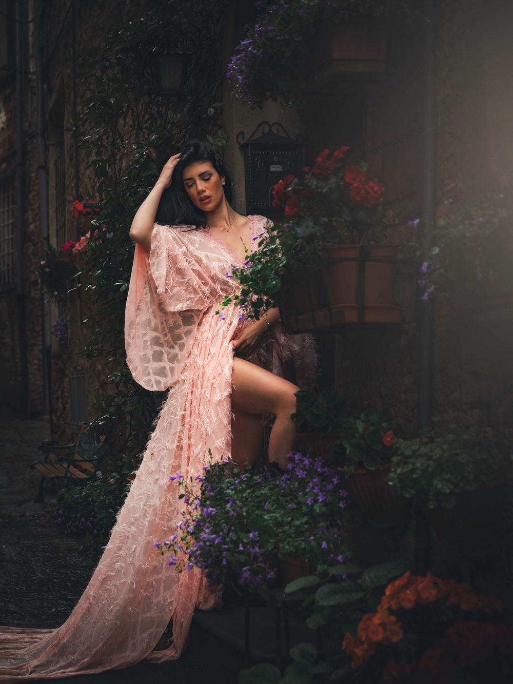 Romantic portrait in flowing pink dress surrounded by purple and red flowers.