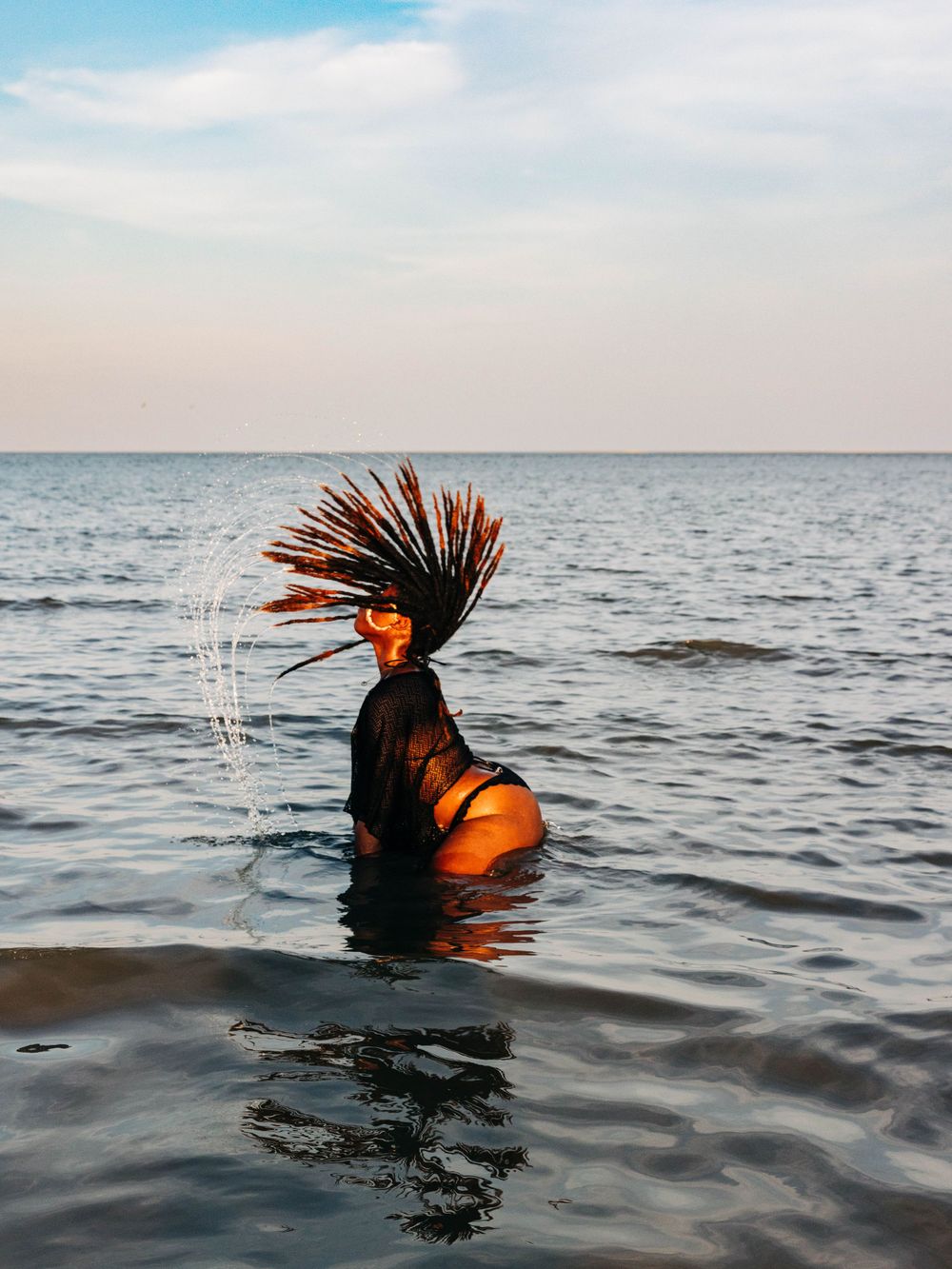 An artistic water portrait capturing hair movement against a serene ocean horizon.