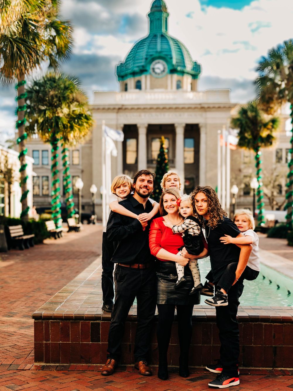 Family portrait in front of historic building with teal dome and palm trees.