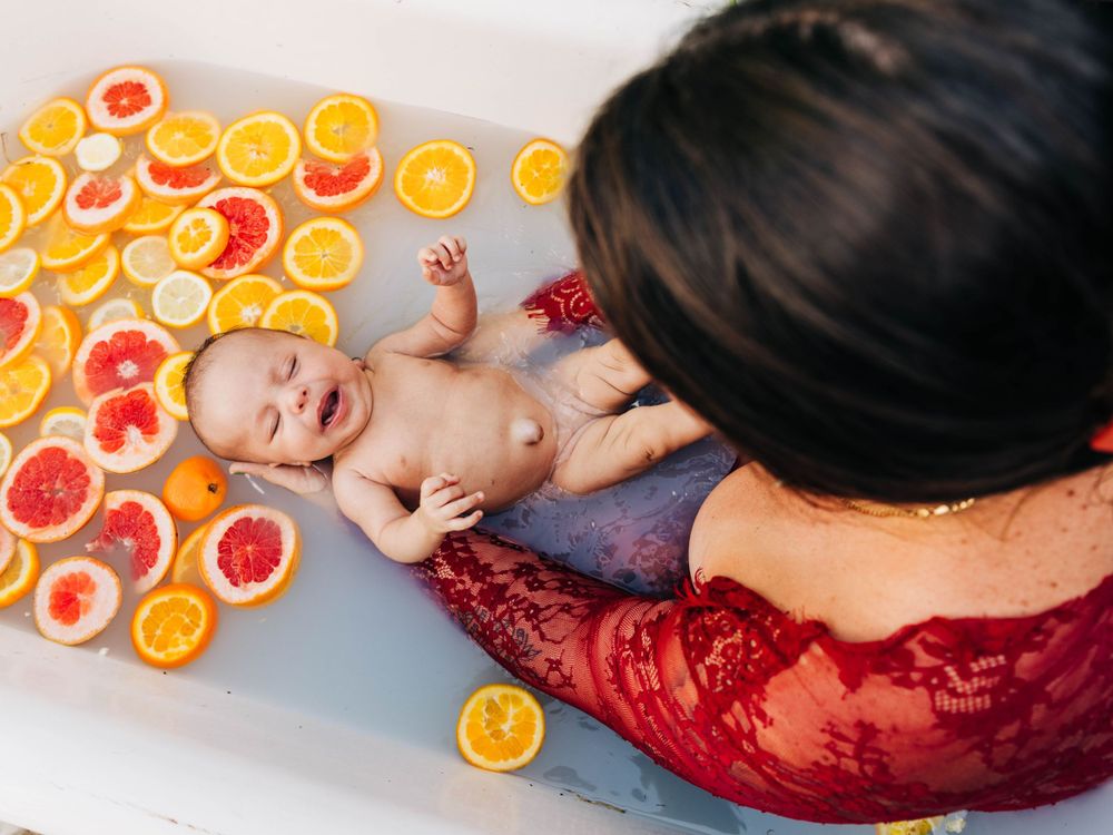 Milk bath photography with citrus slices floating around baby during newborn photoshoot.