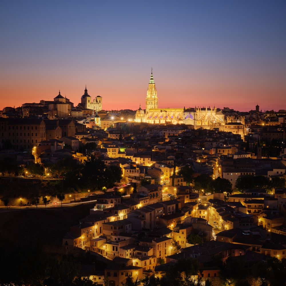 Photo of Cathedral of Toledo, Spain at Blue Hour with the streets lit up and the sky changing from red to blue.