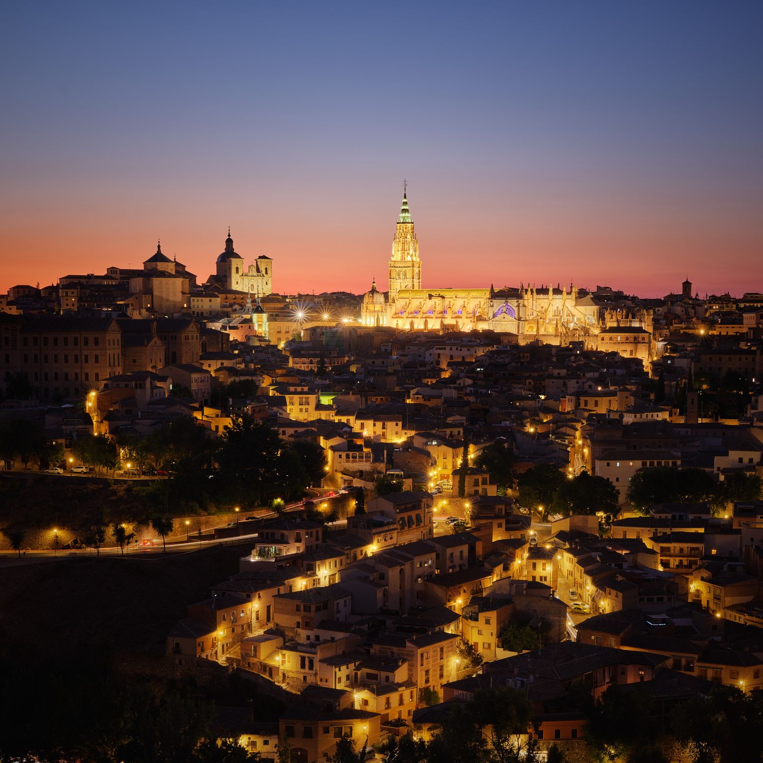 Photo of Cathedral of Toledo, Spain at Blue Hour with the streets lit up and the sky changing from red to blue.