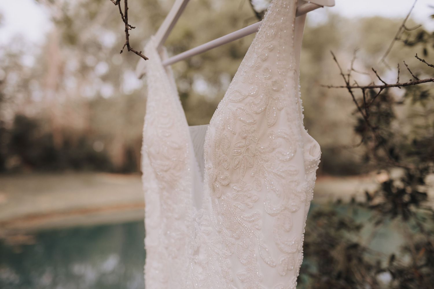 Detailed view of a white lace wedding dress bodice hanging outdoors.