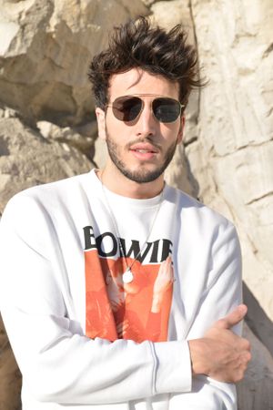 White Bowie sweatshirt and sunglasses against rocky backdrop.