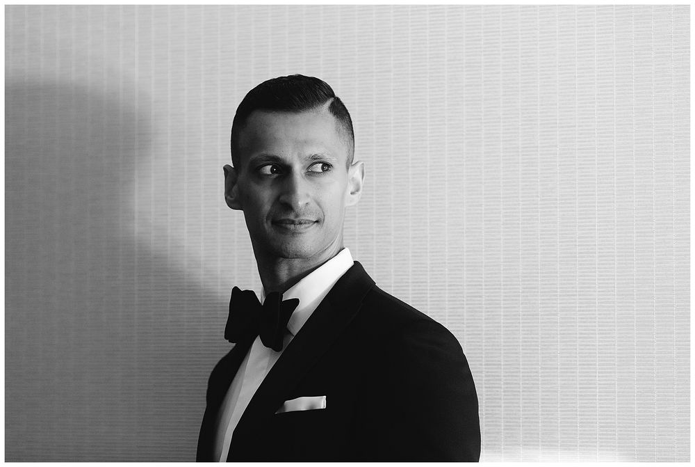 Classic black and white portrait of a groom in a black tuxedo and bow tie.