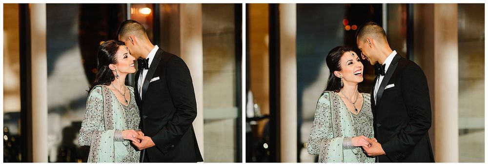 A couple embraces in matching formal attire against an elegant interior setting.