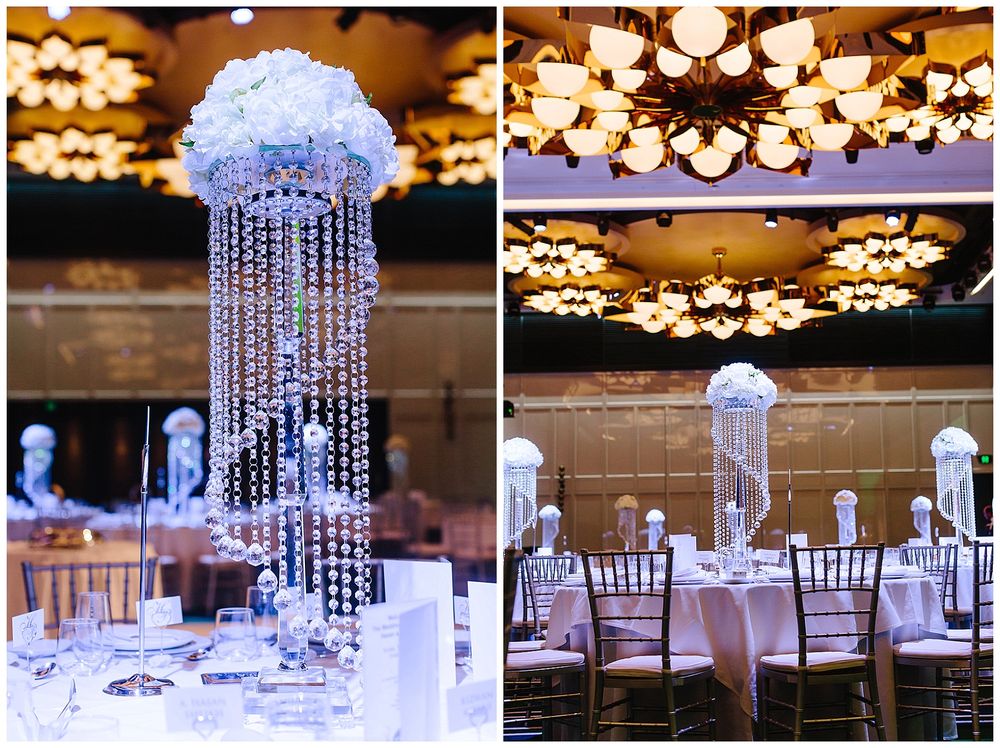Crystal chandelier centerpieces with hanging beads and white floral tops illuminate wedding reception tables.