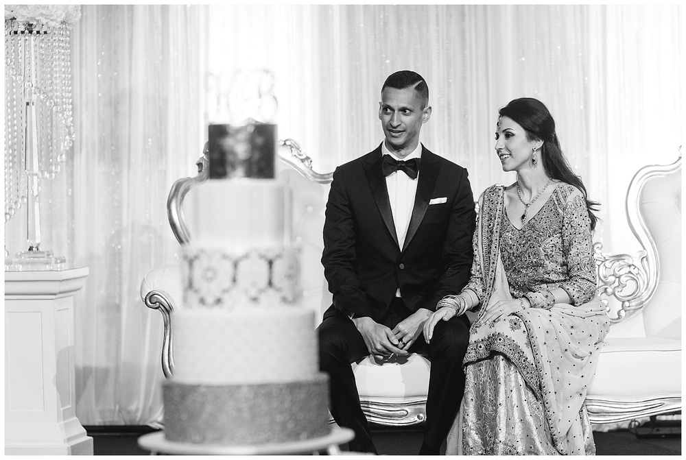 Elegant wedding reception scene with formal attire and decorative cake display.