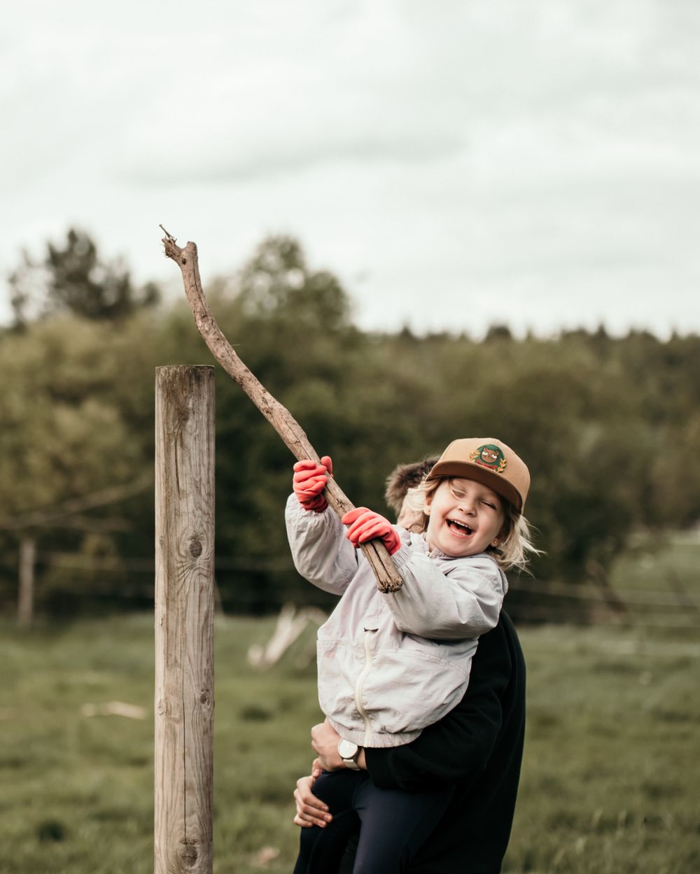 A joyful moment captured outdoors in a green field with a wooden post.