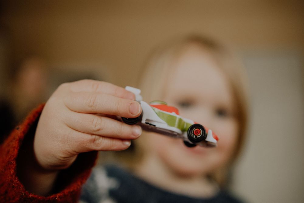 Small toy car being held up against blurred background.