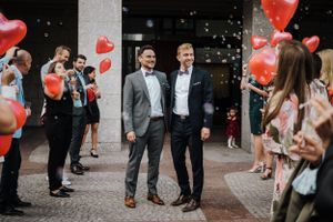 Bräutigamme werden mit Luftballons und Seifenblasen vor dem Standesamt empfangen  LGBTQ+ Hochzeit