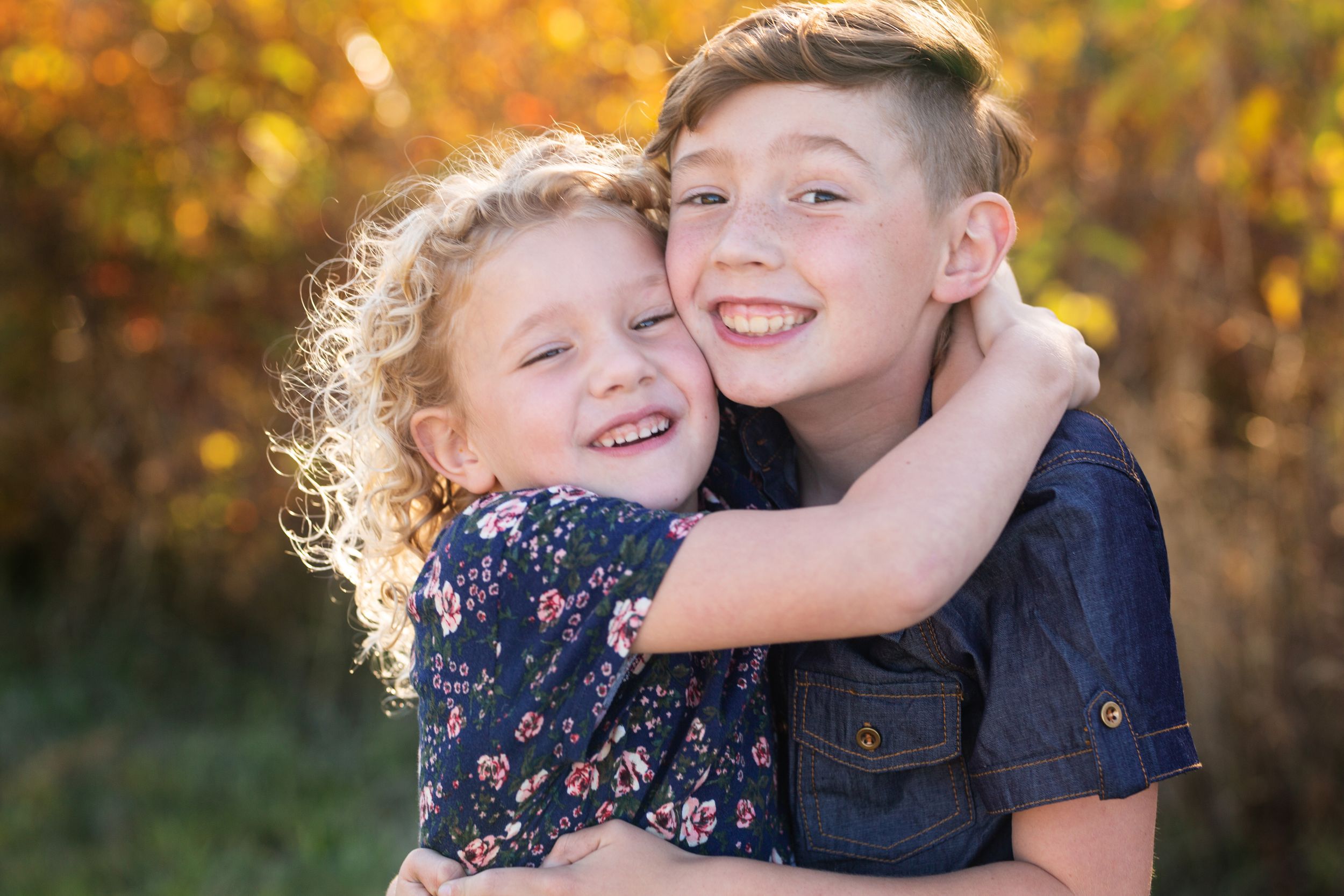 Brother and sister hug in backlit fall colors at a family photo shoot in Portland, Oregon