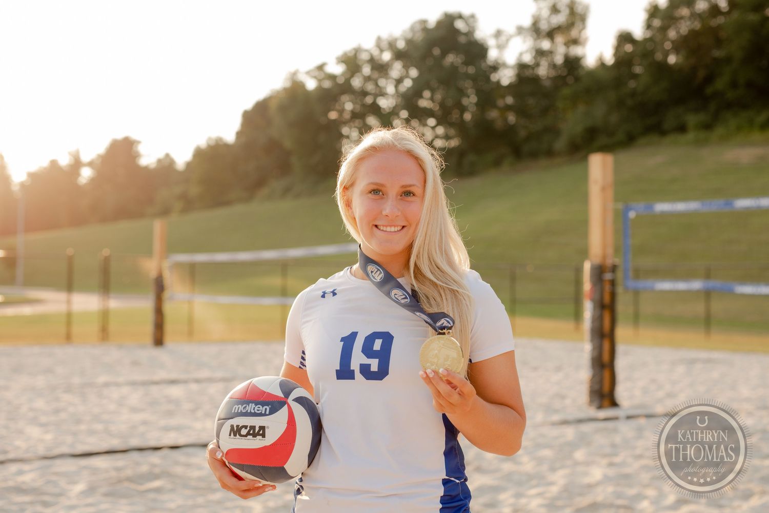 Volleyball player in jersey number 13 holding ball on sand court.