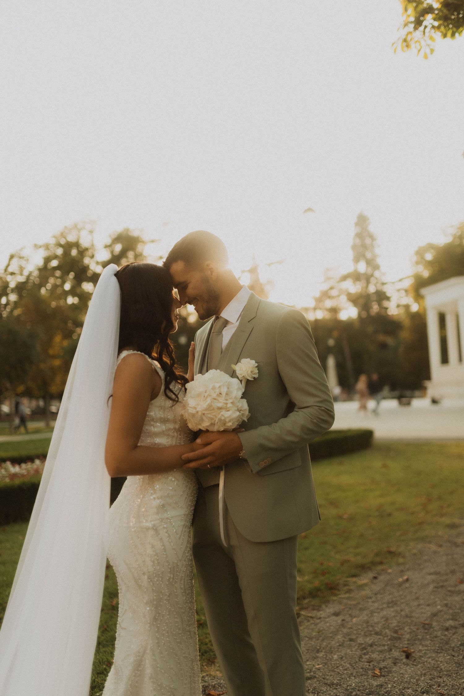 Romantic couple in wedding attire sharing tender moment during golden hour.