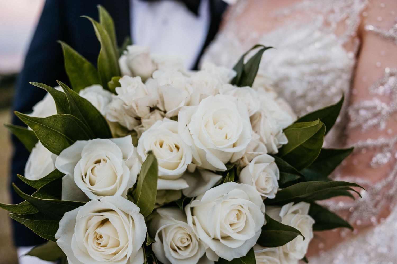 Elegant white rose bouquet with lush green foliage.