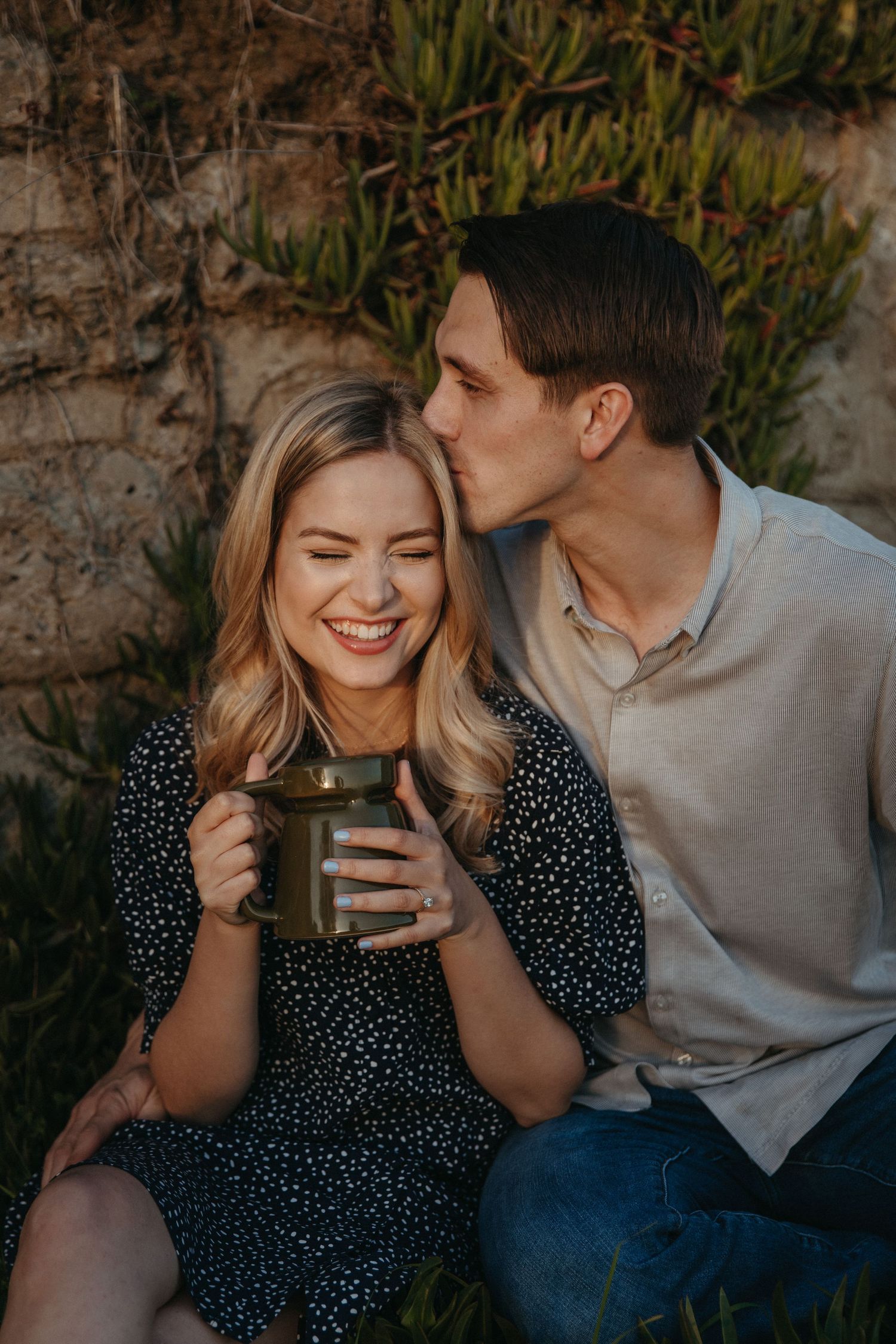 A couple sharing a warm moment together while holding a coffee mug outdoors.