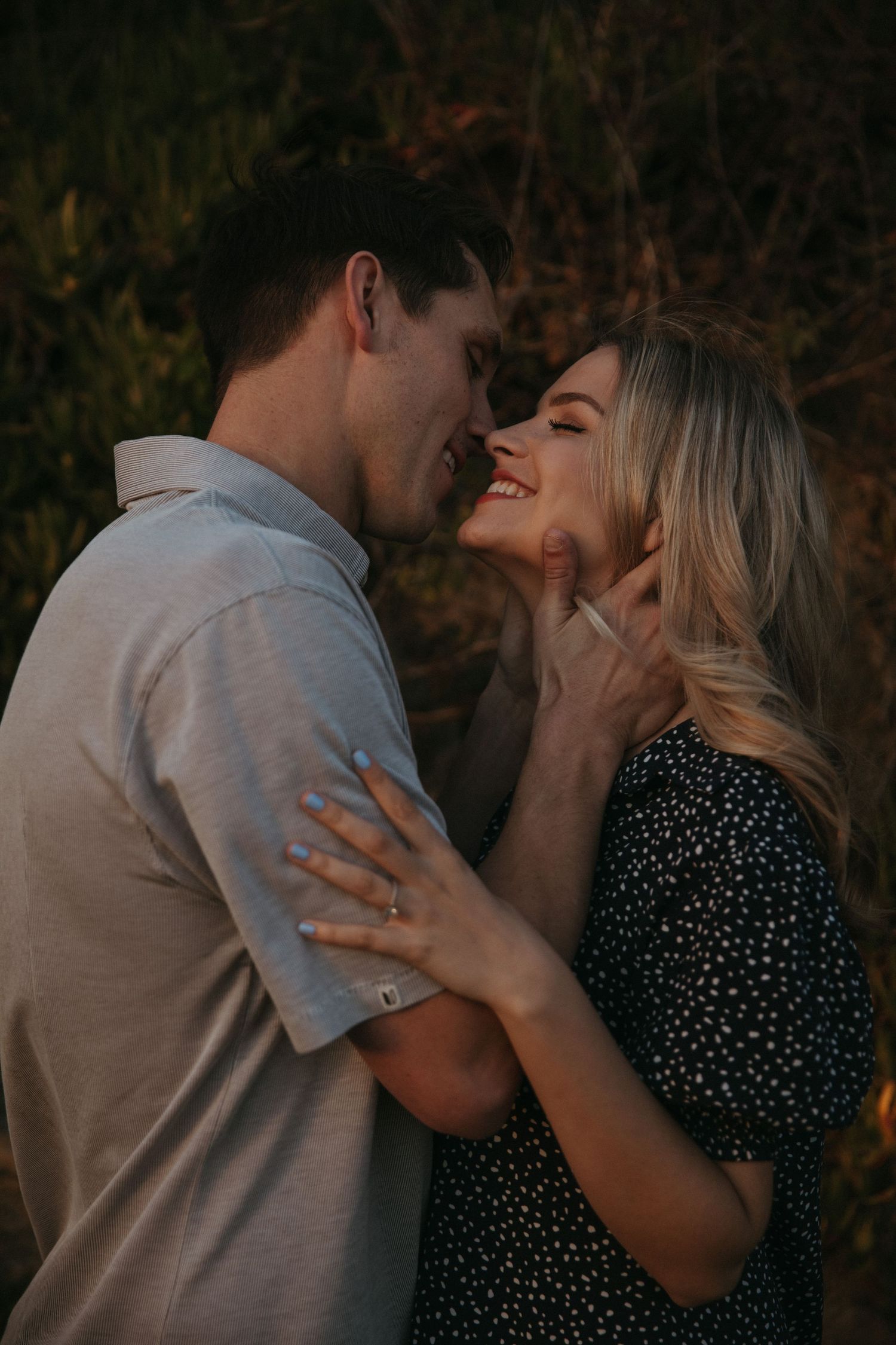 Romantic couple sharing an intimate moment outdoors at sunset with natural lighting and soft expressions.