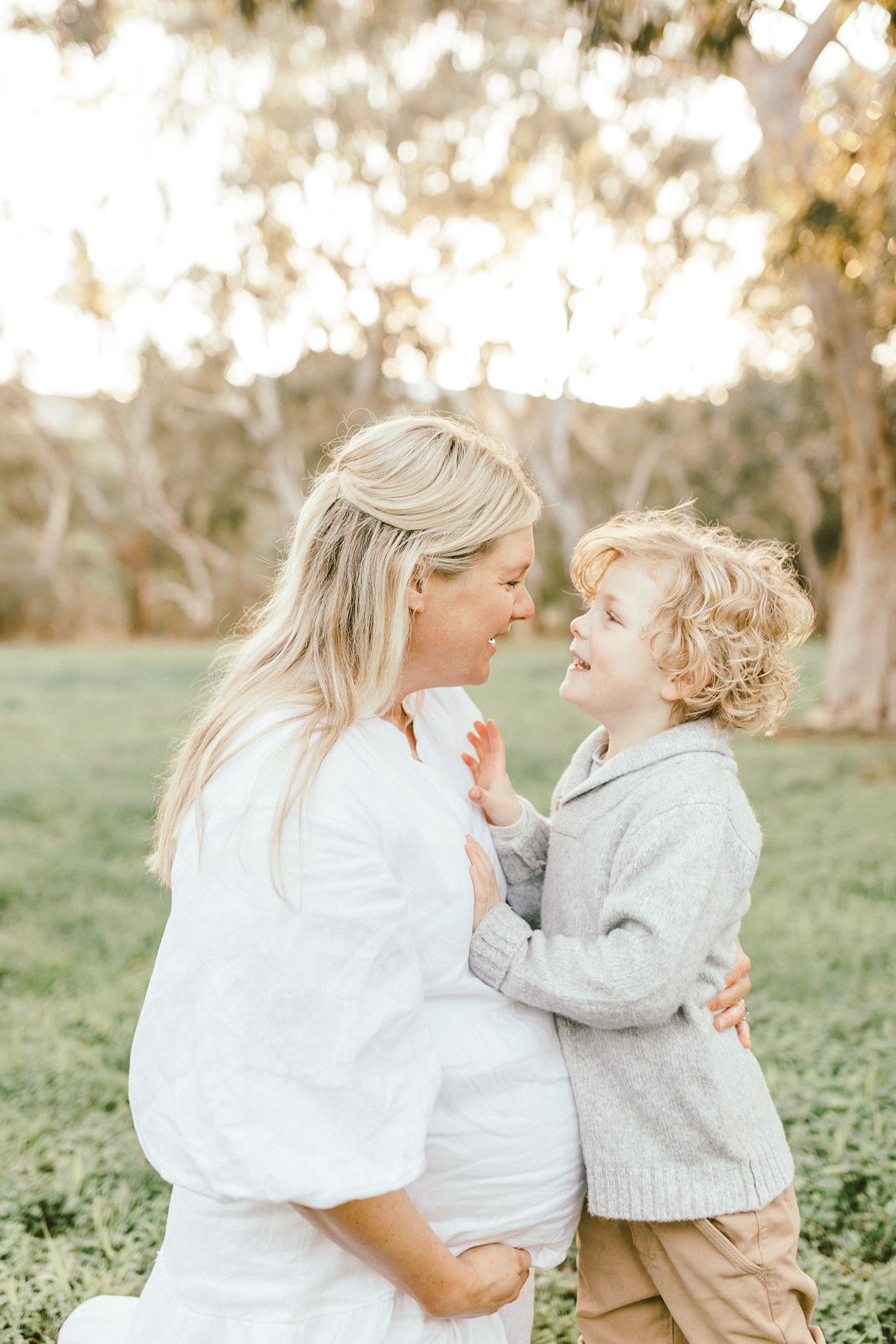 Intimate moment between parent and child sharing laughter in a sun-dappled setting.