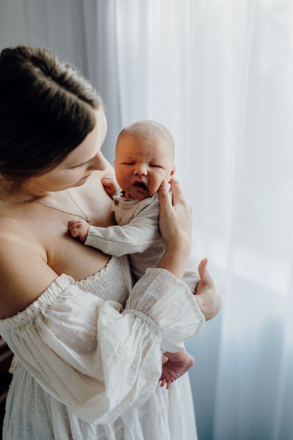Intimate indoor portrait with delicate white clothing in natural window light.