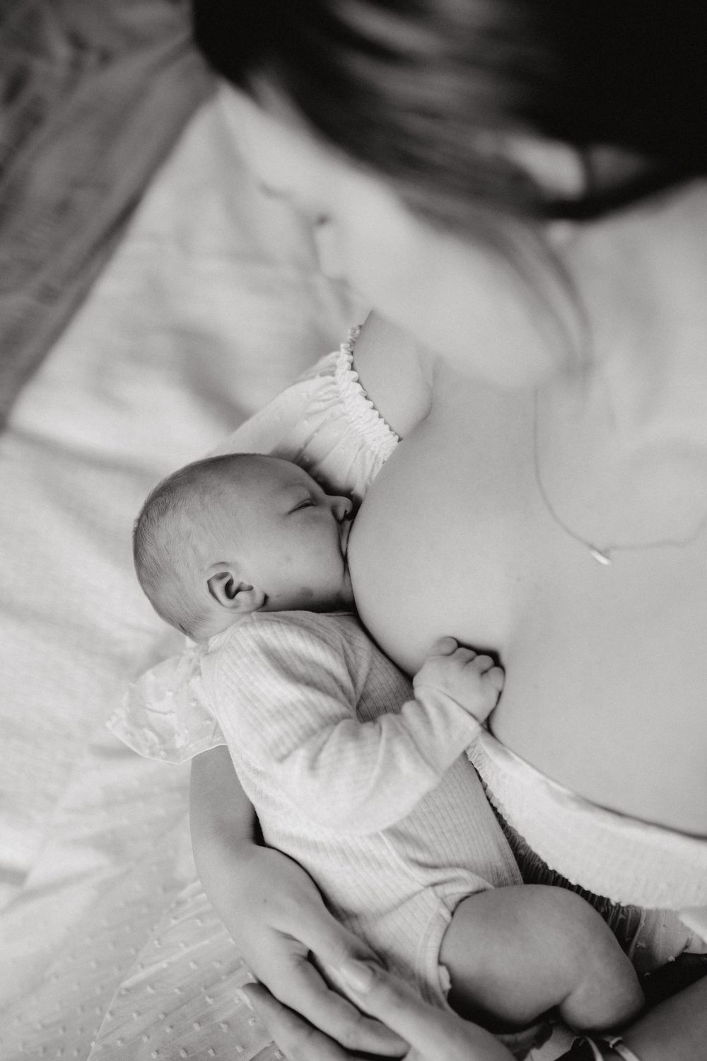 Peaceful newborn baby sleeping in soft white bedding with gentle lighting and shadows.