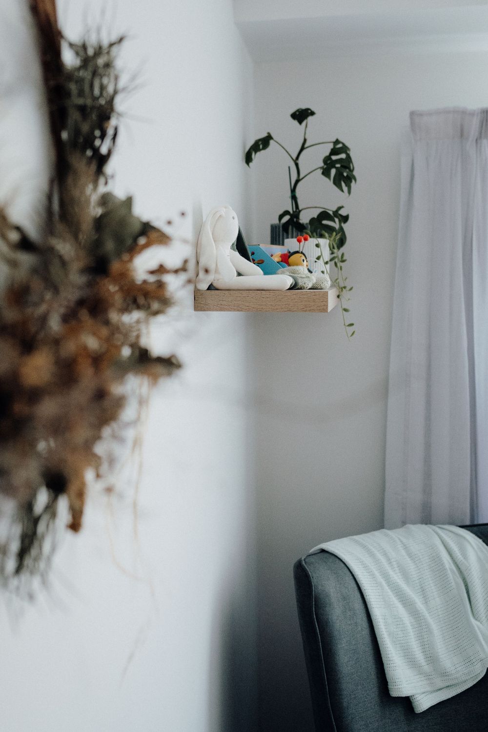 Minimalist nursery shelf with plants and decorative items against white wall.
