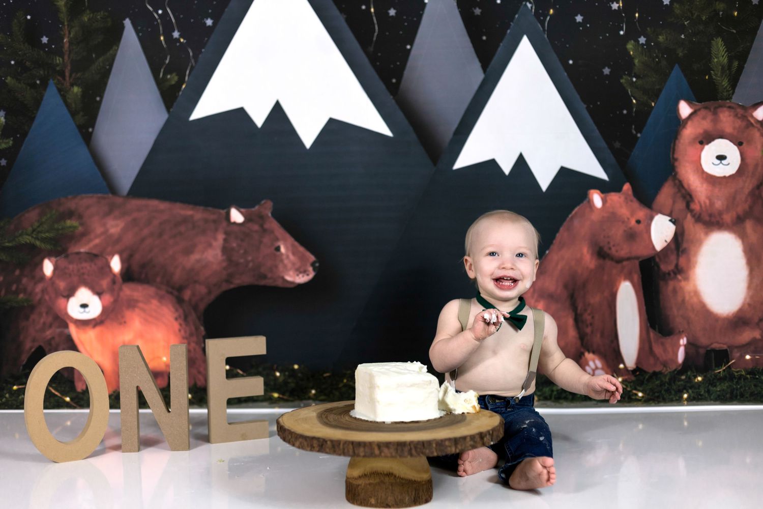 First birthday cake smash setup with mountain backdrop and bear decorations.