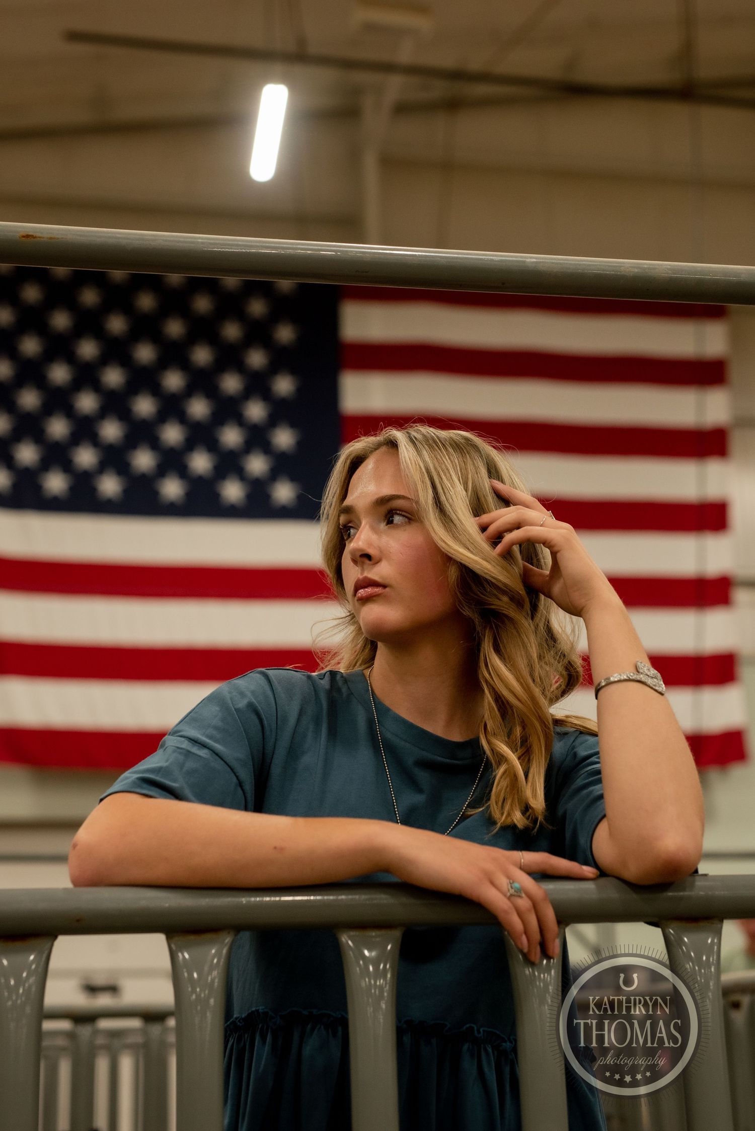A fashion portrait against an American flag backdrop showcases a teal babydoll top and casual style.
