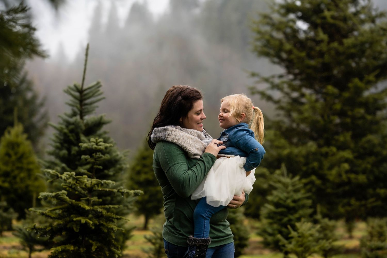 Couple embraces in foggy evergreen forest during outdoor photo session.