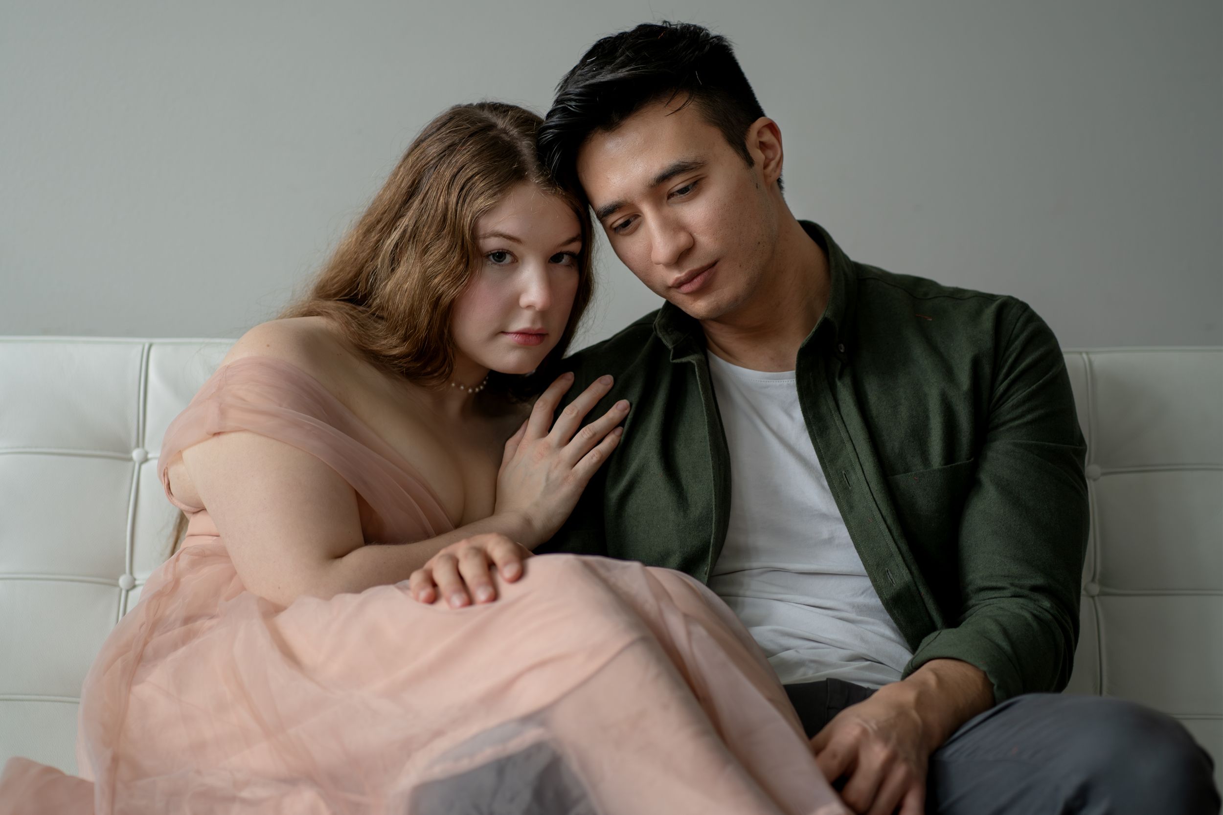 Romantic photo series showing couple in gentle embraces on gray studio backdrop.