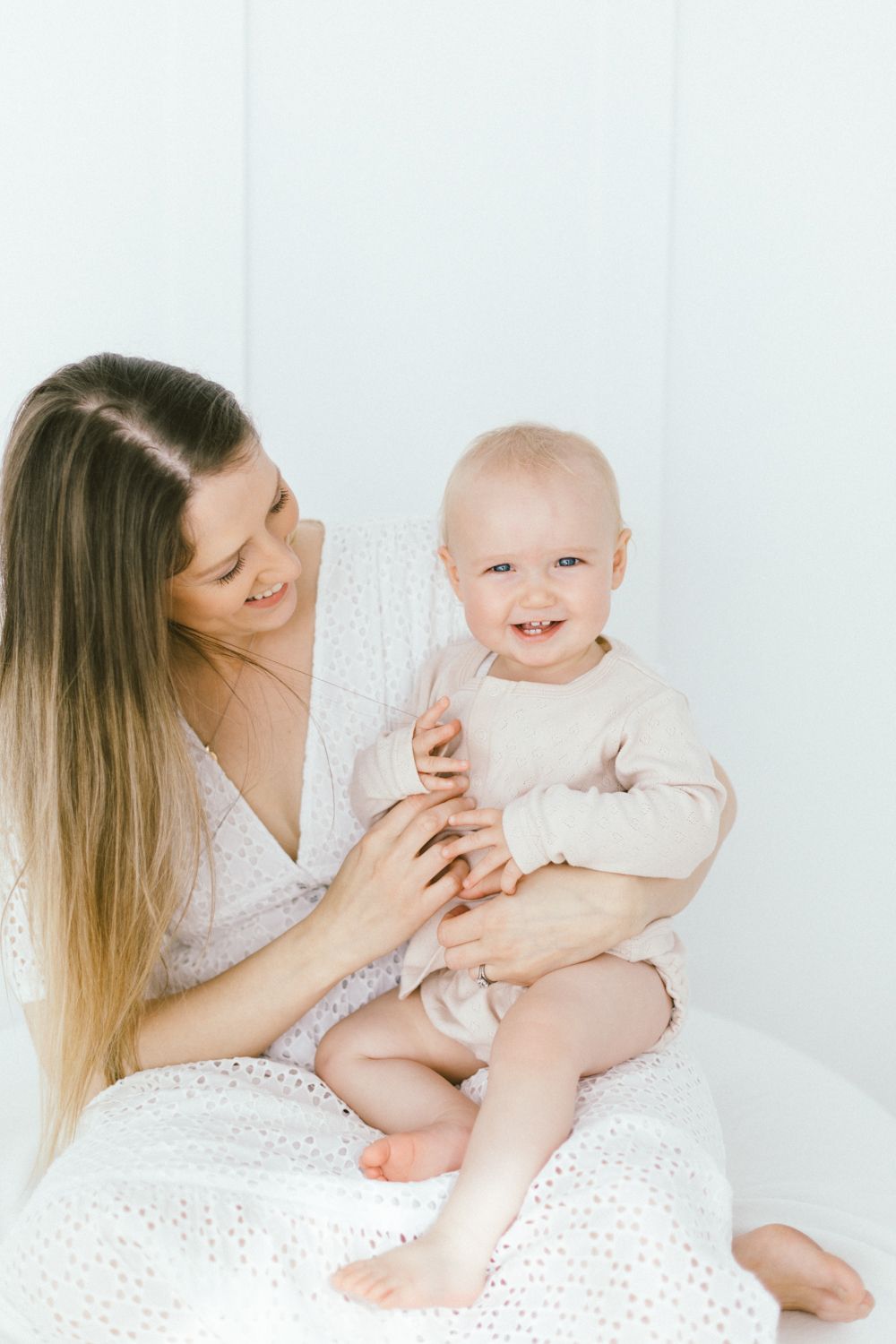 Sweet bonding moment between parent and baby on white bedding.
