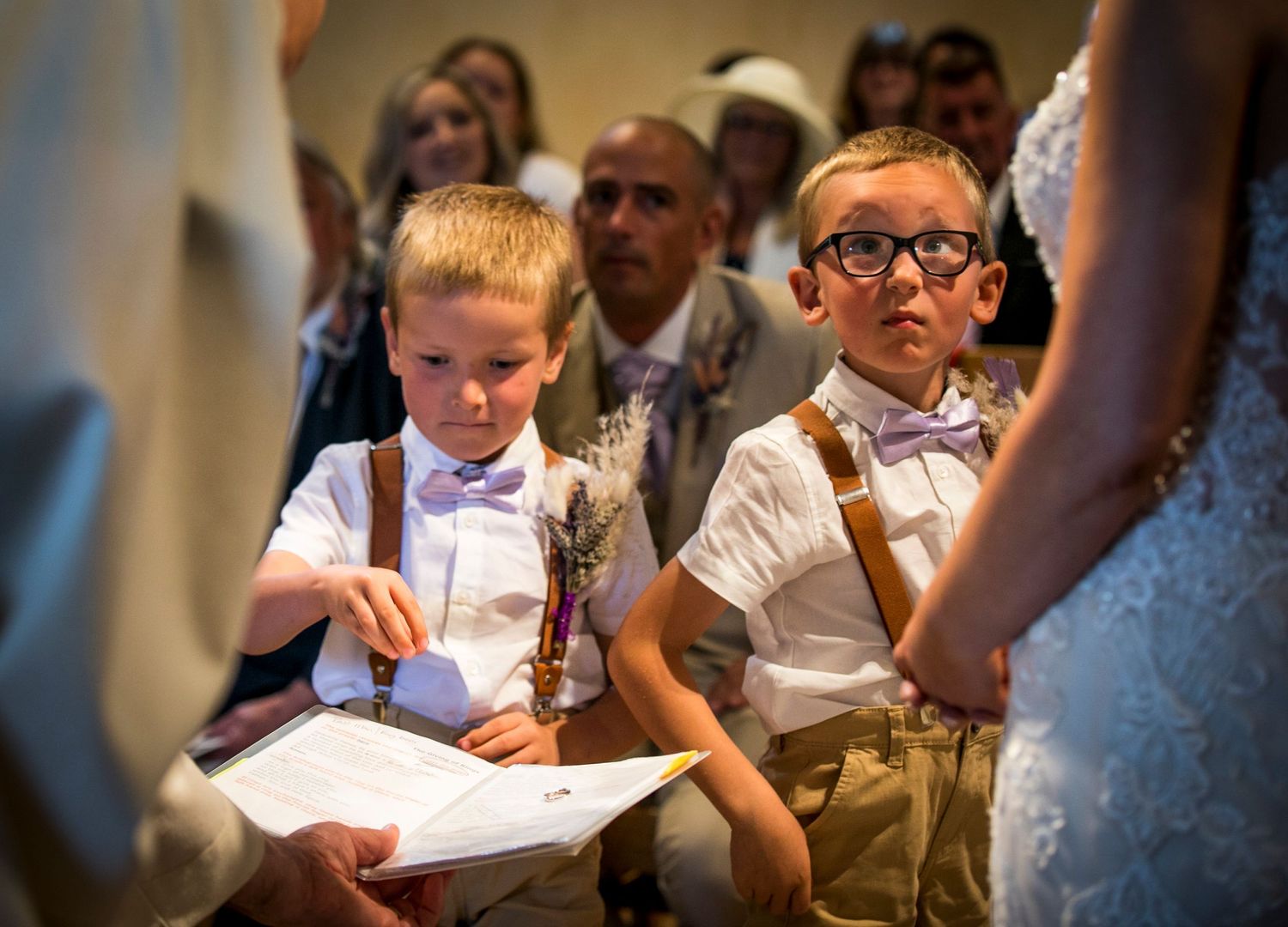 Young wedding guests sitting in church pews during the ceremony.