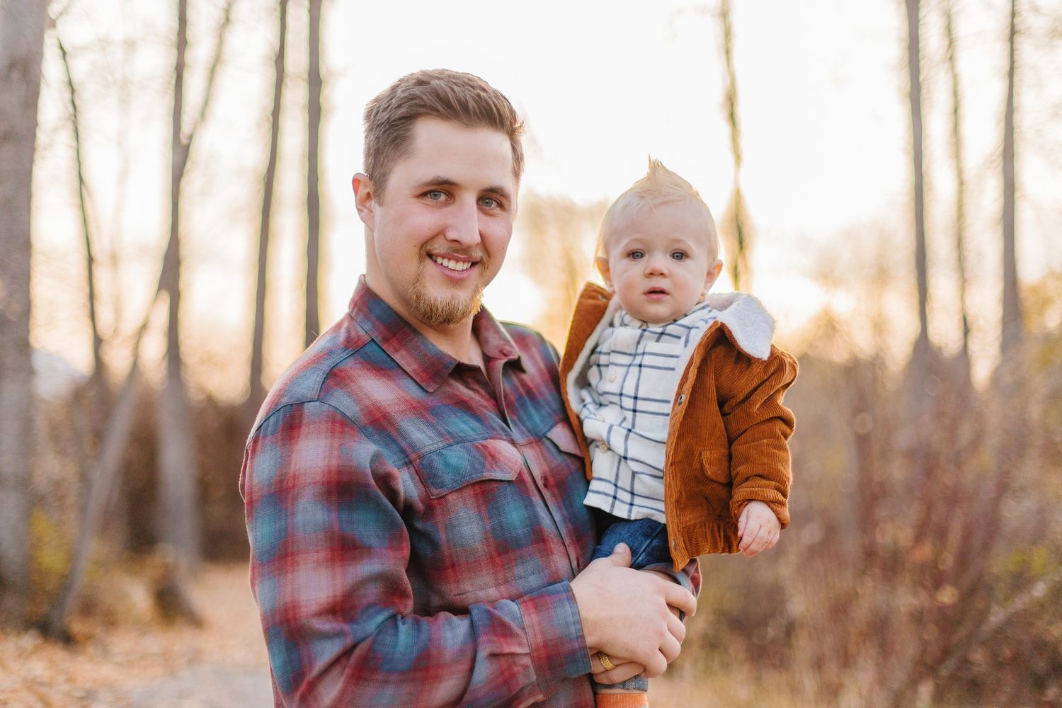 Family poses together on wooden walkway surrounded by fall foliage.