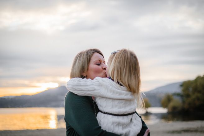 Couple embraces during sunset photoshoot by mountain lake.