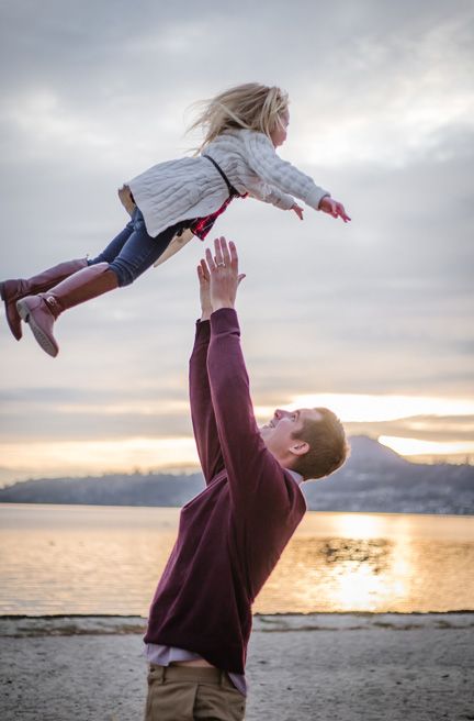 A playful scene of lifting and twirling at sunset on a beach.