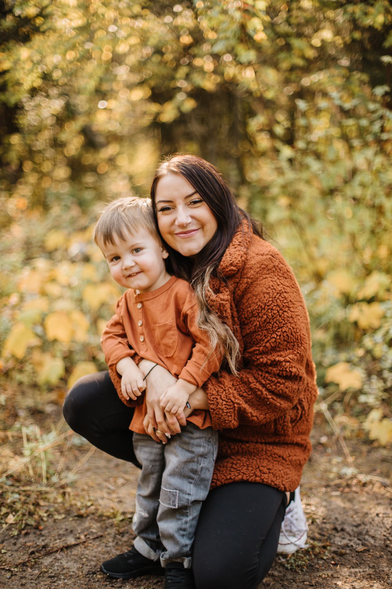 An autumn photoshoot in a golden forest with warm lighting and fallen leaves.