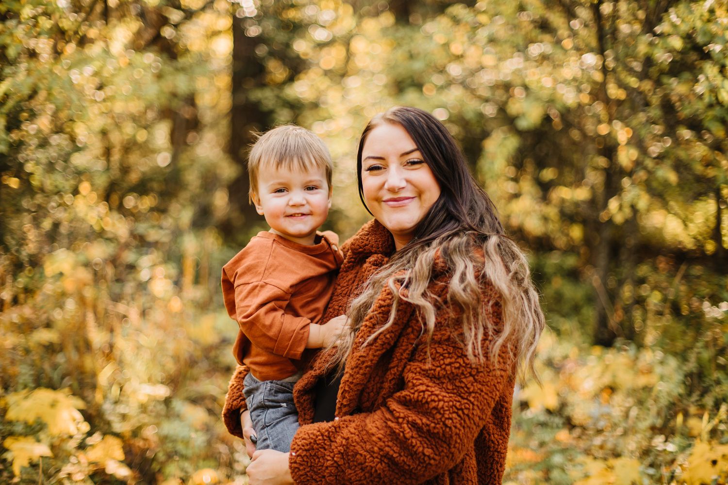 A warm autumn photoshoot in a forest with golden sunlight filtering through trees.
