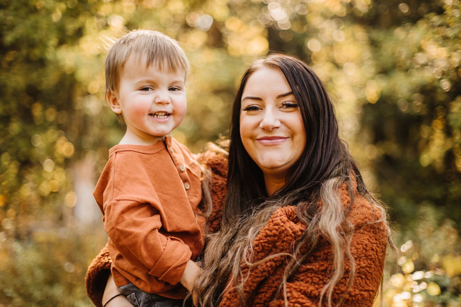 A cozy autumn photoshoot in a forest setting with warm brown and orange tones.