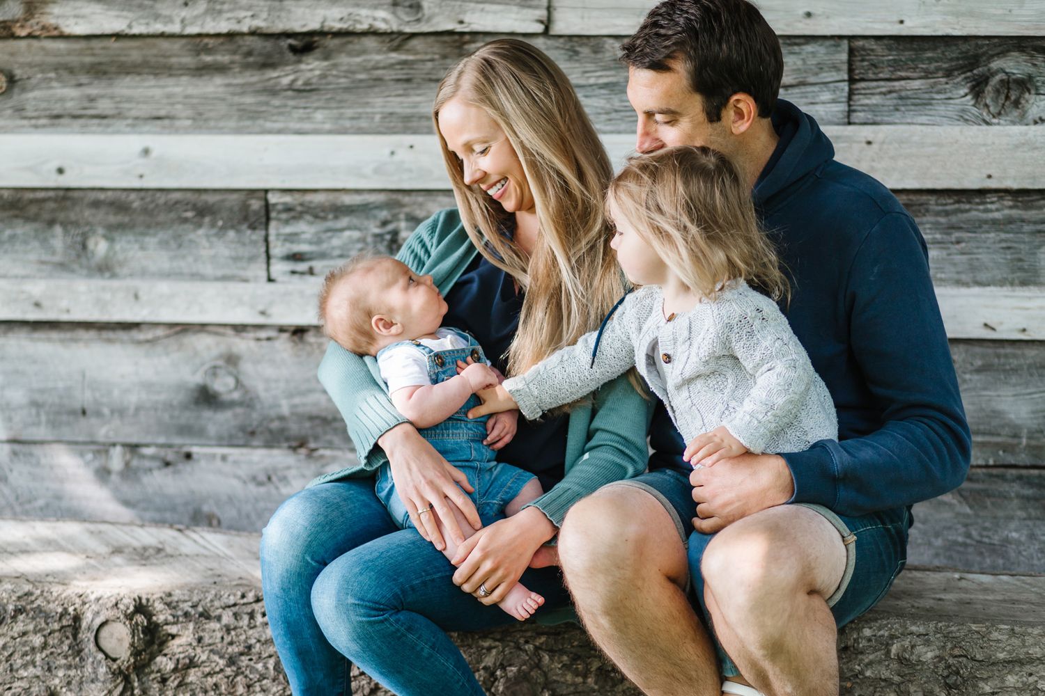 Family sitting together on rustic wooden steps during an outdoor photo session.
