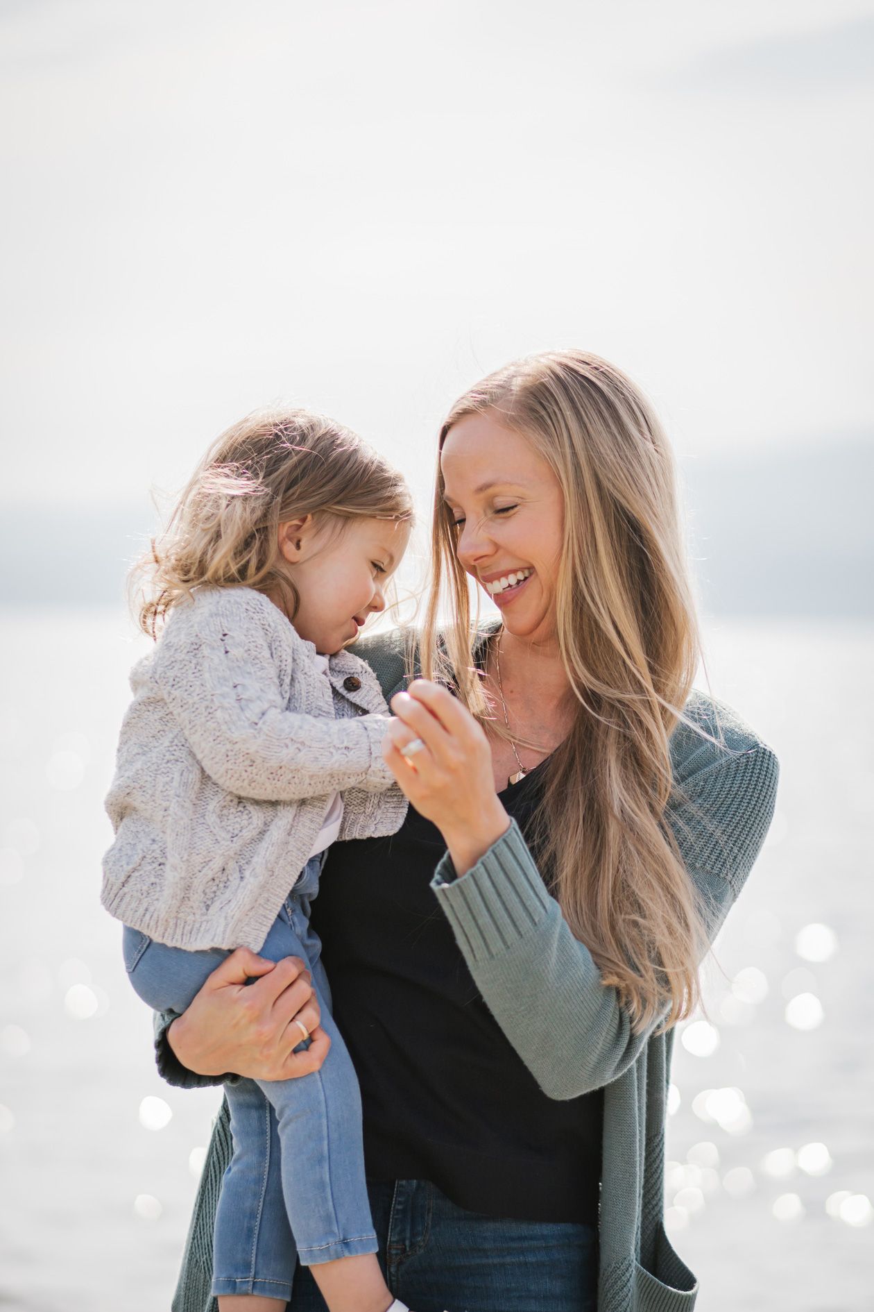 Joyful interaction between two people against a bright, bokeh background near water.