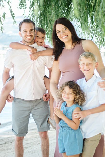 Family group photo under weeping willow trees by the water.