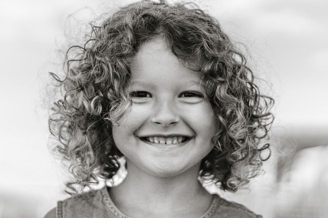 Series of black and white portraits showing curly hair and genuine smiles.